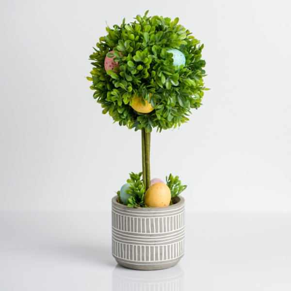 A grey and white pot with a green plant and pastel-colored eggs inside